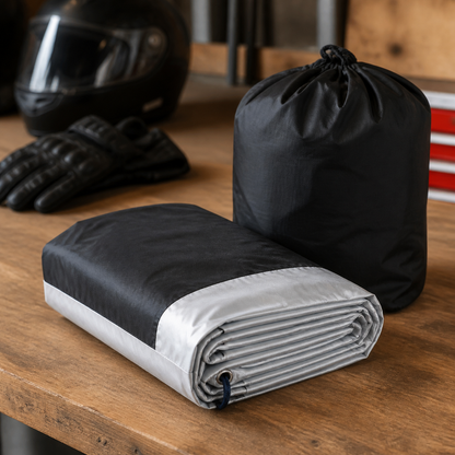 Folded black and silver motorcycle cover with storage bag
