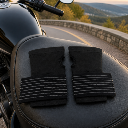 Two black wrist wraps on a motorcycle seat at a road overlook